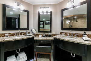 Bathroom with tasteful backsplash, a shower stall, and two vanities