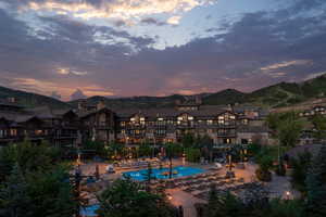 Pool at dusk with a community pool, a patio, and a mountain view