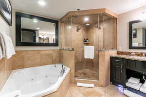 Full bathroom featuring a shower stall, vanity, a jetted tub, tile walls, and light tile patterned floors