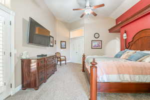 Bedroom featuring light colored carpet, vaulted ceiling, and ceiling fan