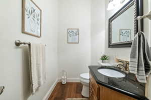 Half bath with dark wood-type flooring and vanity