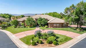 Mediterranean / spanish-style home with a tiled roof, a front yard, and stone siding