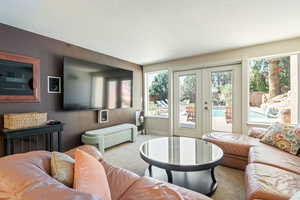 Living room featuring french doors, carpet floors, and a textured ceiling