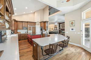 Kitchen with a ceiling fan, a breakfast bar area, decorative backsplash, dark wood-type flooring, and high vaulted ceiling