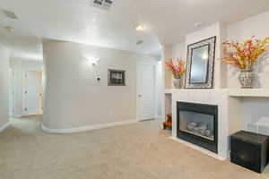 Unfurnished living room featuring carpet flooring and a tiled fireplace