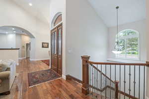 Entrance foyer with high vaulted ceiling, arched walkways, hardwood / wood-style flooring, and recessed lighting