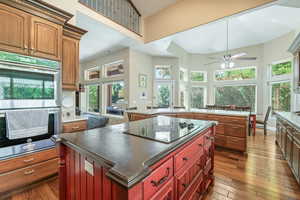 Kitchen with a center island, double oven, a high ceiling, ceiling fan, and dark wood-type flooring