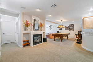 Game room featuring a tiled fireplace, light carpet, and pool table