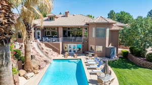 Rear view of property featuring a patio area, a lawn, stucco siding, and a tiled roof