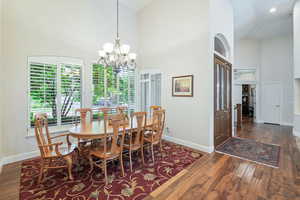 Dining area featuring high vaulted ceiling, dark wood-type flooring, and a chandelier