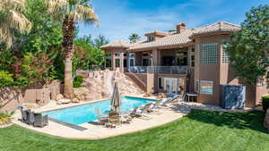 Rear view of property with stucco siding, a patio area, a tile roof, a lawn, and stairway