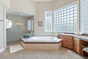 Bathroom featuring a stall shower, a garden tub, and vanity