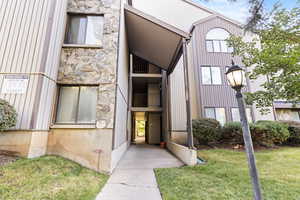 Property entrance featuring stone siding and a lawn