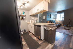 Kitchen featuring light countertops, stainless steel appliances, open floor plan, a textured ceiling, and white cabinetry