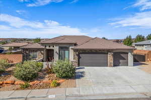 View of front of house featuring stone siding, an attached garage, and a tiled roof