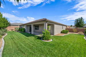 Rear view of house with stucco siding, a fenced backyard, and a patio area