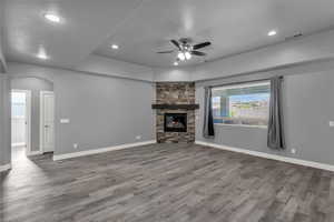 Unfurnished living room with ceiling fan, light wood-style flooring, arched walkways, a fireplace, and recessed lighting