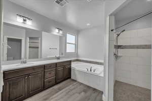 Full bathroom with a bath, a tile shower, double vanity, and light wood finished floors
