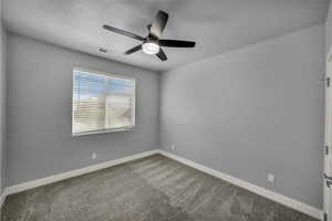 Carpeted spare room featuring baseboards and ceiling fan