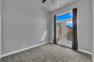 Carpeted empty room featuring french doors and a ceiling fan