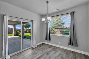 Unfurnished dining area featuring a chandelier and light wood-style flooring