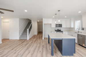 Kitchen with two tone cabinets, stainless steel appliances, a kitchen island, pendant lighting, and a breakfast bar