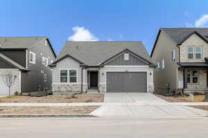 Craftsman-style home with board and batten siding, stone siding, roof with shingles, an attached garage, and concrete driveway