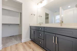 Bathroom featuring a spacious closet, double vanity, light wood finished floors, and recessed lighting