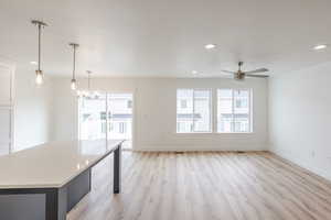 Kitchen with light wood-style floors, a center island, a kitchen bar, a chandelier, and ceiling fan