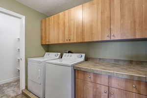 Washroom featuring cabinet space, a textured ceiling, and washing machine and clothes dryer