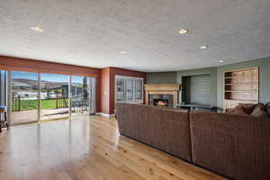Living room with a tile fireplace, recessed lighting, hardwood / wood-style floors, and a textured ceiling