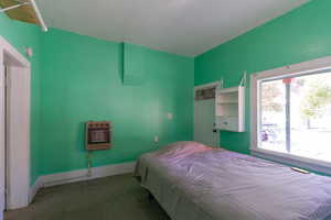 Carpeted bedroom featuring heating unit and baseboards