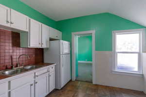Kitchen with white cabinets, freestanding refrigerator, dark countertops, a wainscoted wall, and tile walls