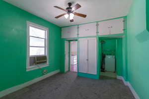 Unfurnished bedroom featuring washer / clothes dryer, carpet, and ceiling fan