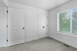 Unfurnished bedroom with light colored carpet and a closet