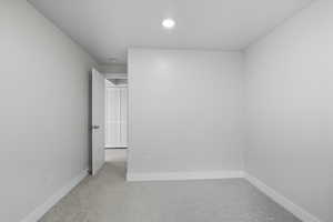 Unfurnished bedroom featuring light carpet and baseboards