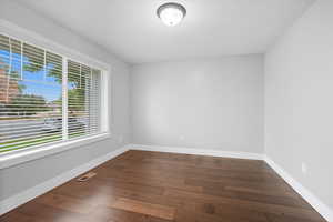 Spare room featuring baseboards and dark wood-type flooring