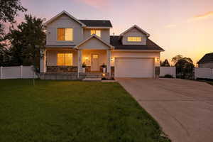 View of front of property featuring stone siding, covered porch, driveway, a garage, and board and batten siding