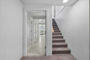 Staircase with tile patterned flooring, recessed lighting, and carpet