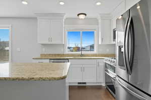 Kitchen featuring appliances with stainless steel finishes, white cabinetry, light stone counters, recessed lighting, and dark wood-style flooring