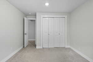 Unfurnished bedroom featuring light colored carpet and a closet