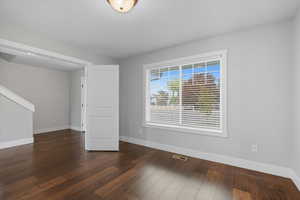 Spare room with baseboards and dark wood-style flooring