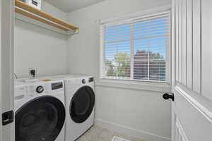 Laundry room with washing machine and dryer and light tile patterned floors