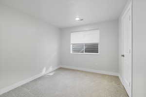 Unfurnished bedroom with light carpet and baseboards