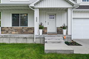 Doorway to property with stone siding, covered porch, and board and batten siding