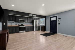 Kitchen featuring appliances with stainless steel finishes, light countertops, light wood finished floors, recessed lighting, and arched walkways