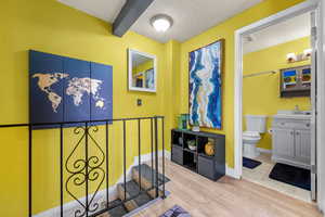 Hall with light wood-type flooring, a textured ceiling, and beam ceiling