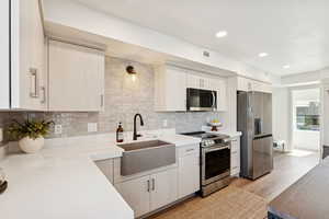 Kitchen with stainless steel appliances, tasteful backsplash, light wood-type flooring, recessed lighting, and light stone countertops
