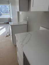 Kitchen featuring white cabinets and light stone countertops