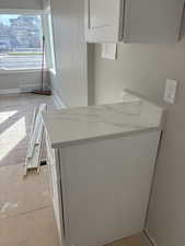 Detailed view of white cabinetry, a peninsula, and light stone countertops